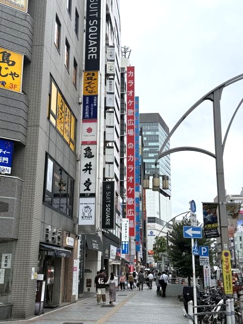 御徒町駅前からアメ横方面を見た通りの様子。スーツスクエアなどの看板が並ぶ商業ビル群。