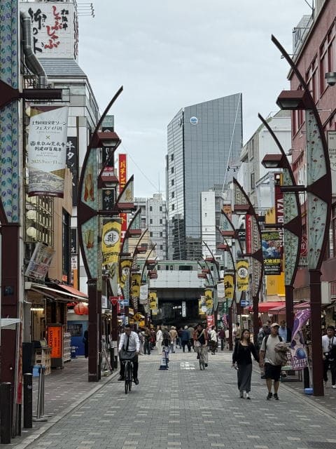 アメ横商店街通りの様子。旗が並び、人通りが多い。正面にJRの高架が見える。