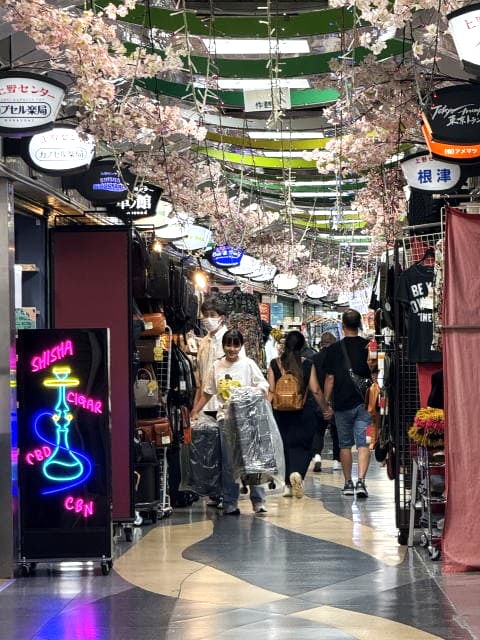 アメ横センタービルの屋内通路。ネオンサインと桜の飾りがあり、観光客が歩いている。