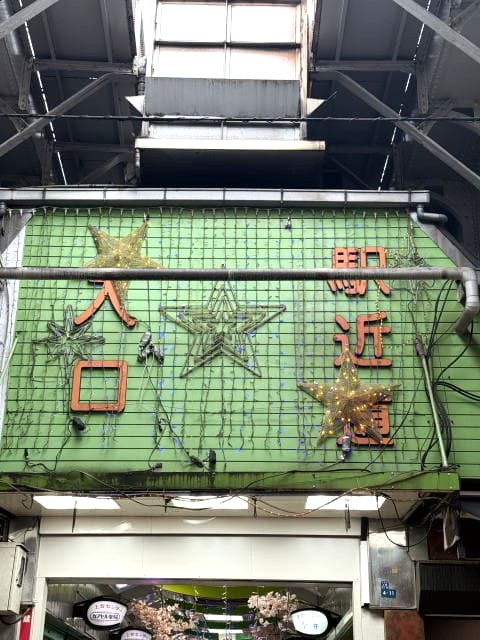 アメ横センター入口の古い緑色の看板。星型のイルミネーションが飾られている。
