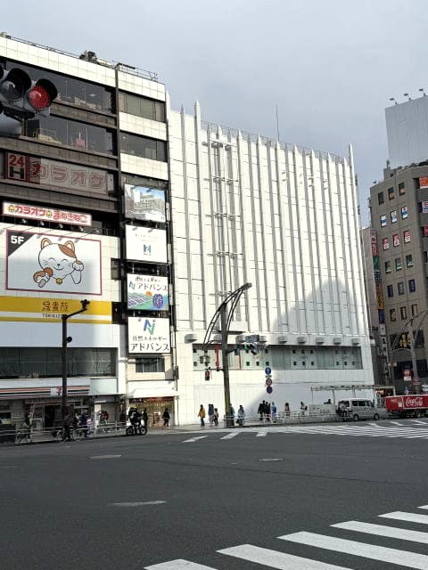 上野駅前の交差点。白い建物と人通りが見える昼の風景。