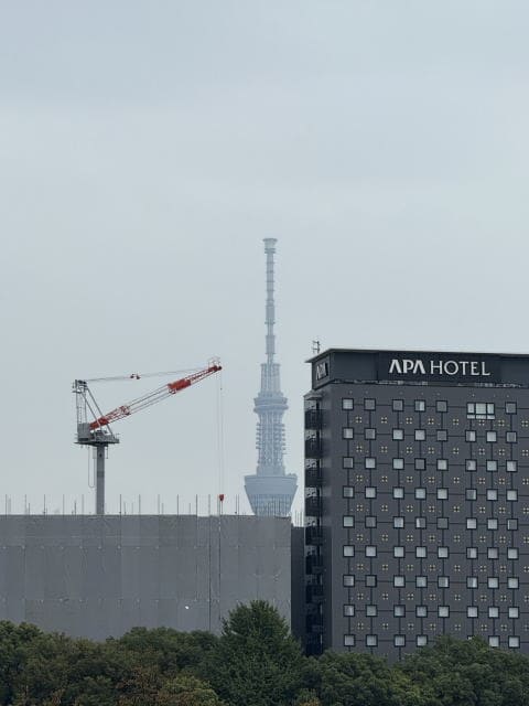 不忍池越しに見えるスカイツリーとアパホテル。曇り空の秋の午後