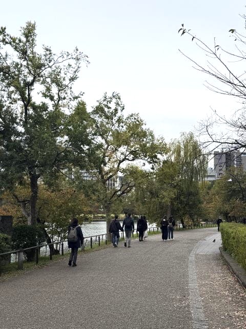 不忍池の遊歩道を歩く人々と紅葉した木々
